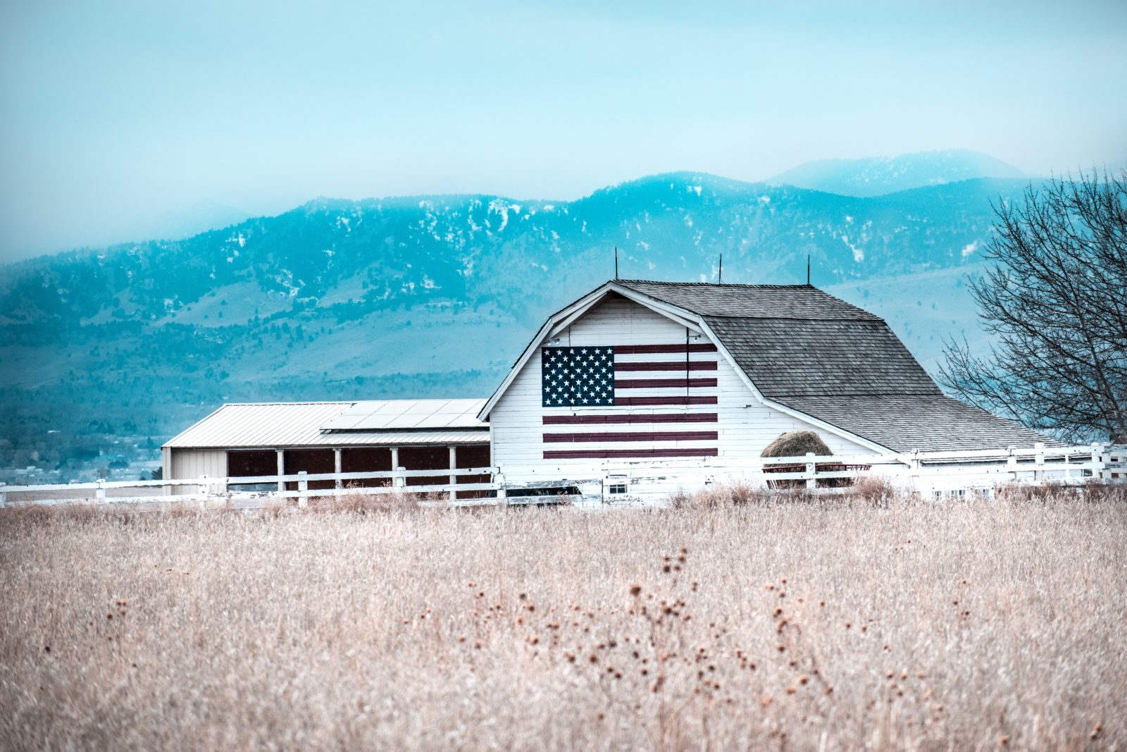 white barn with painted American flag in field with blue sky